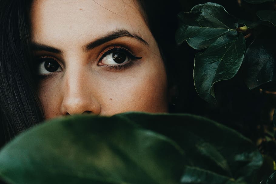 half faced woman near green leaves, selective focus photography of woman hiding in leaves, HD wallpaper