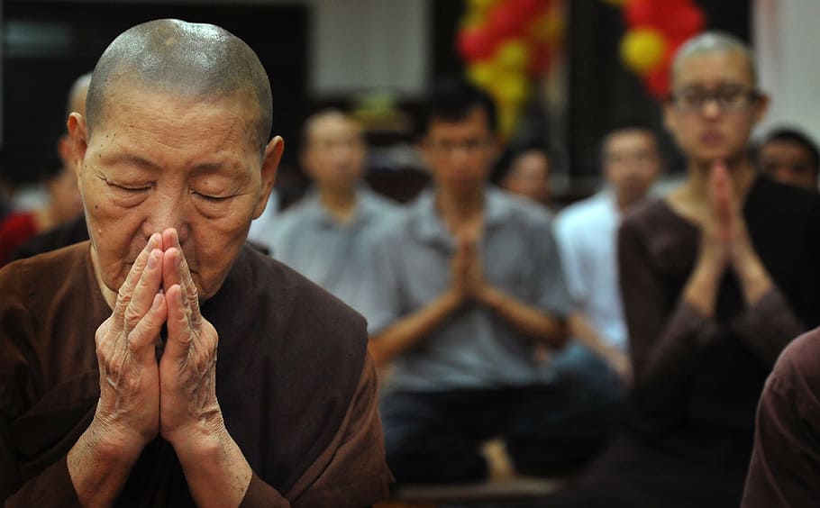 selective photo of woman praying inside room, theravada buddhism