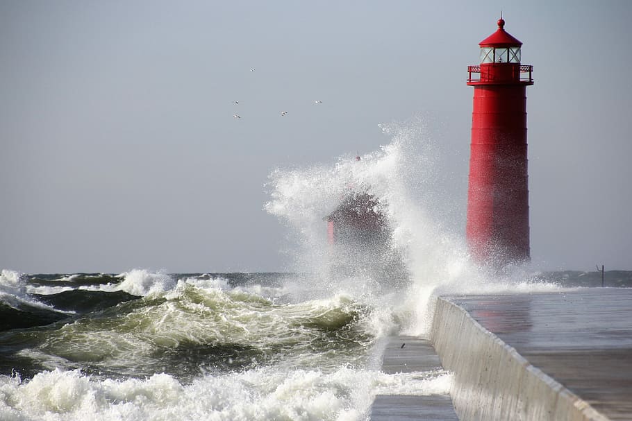 waves crushing the red lighthouse under gray sky during daytime, ocean water crashing on red lighthouse during daytime HD wallpaper