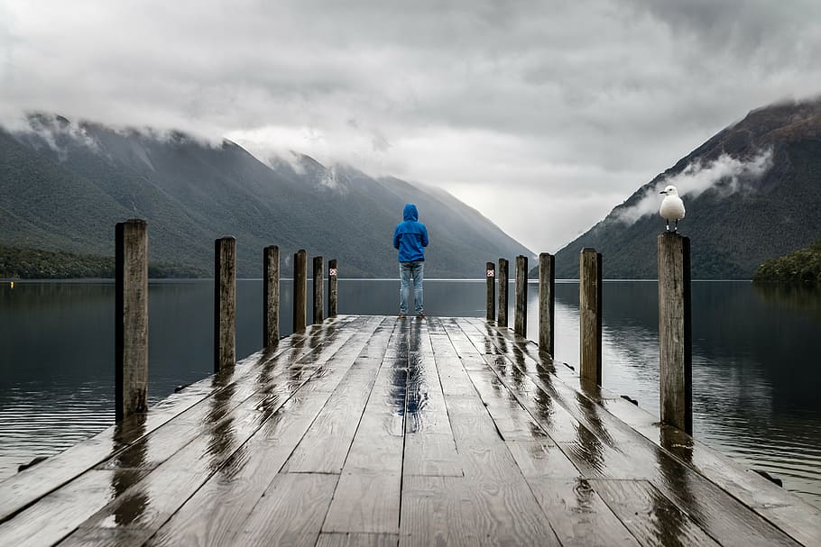person standing on dock beside calm body of water, mountain HD wallpaper
