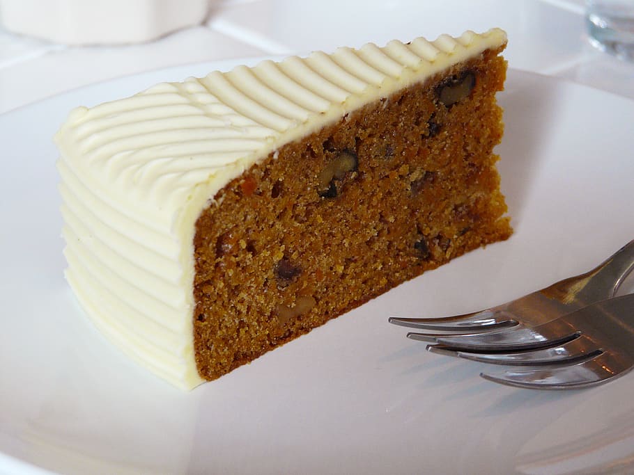 slice cake on plate with silver forks, carrot cake, cream, cheese
