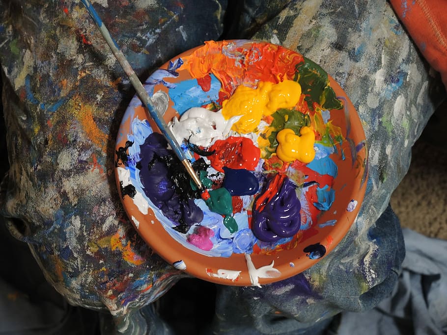 mixed paints in a plate, assorted-color paint on orange bowl with paint brush