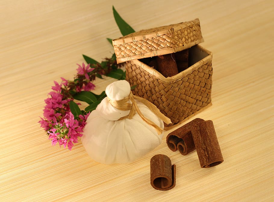 pink flowers beside brown woven basket, spices, herbal massage