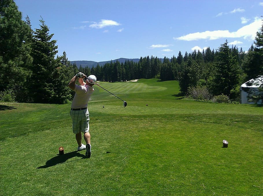 man strikes golf ball with golf club, golfing, golfer, swinging club