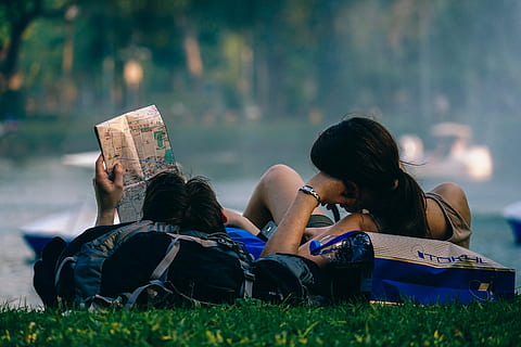 Tourist Backpackers Looking at a Map, couple lying beside body of water while holding map HD wallpaper