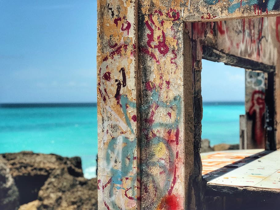 vandalized wall under sunny sky, multicolored painted wooden frame near green sea HD wallpaper