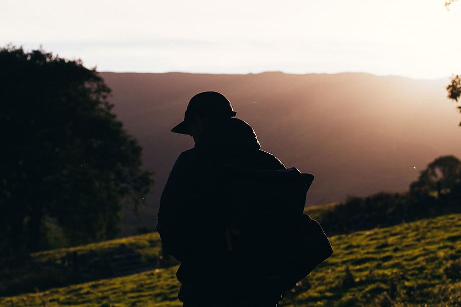 silhouette photo of person carrying backpack during daytime, silhouette photo of person walking on mountain slope HD wallpaper