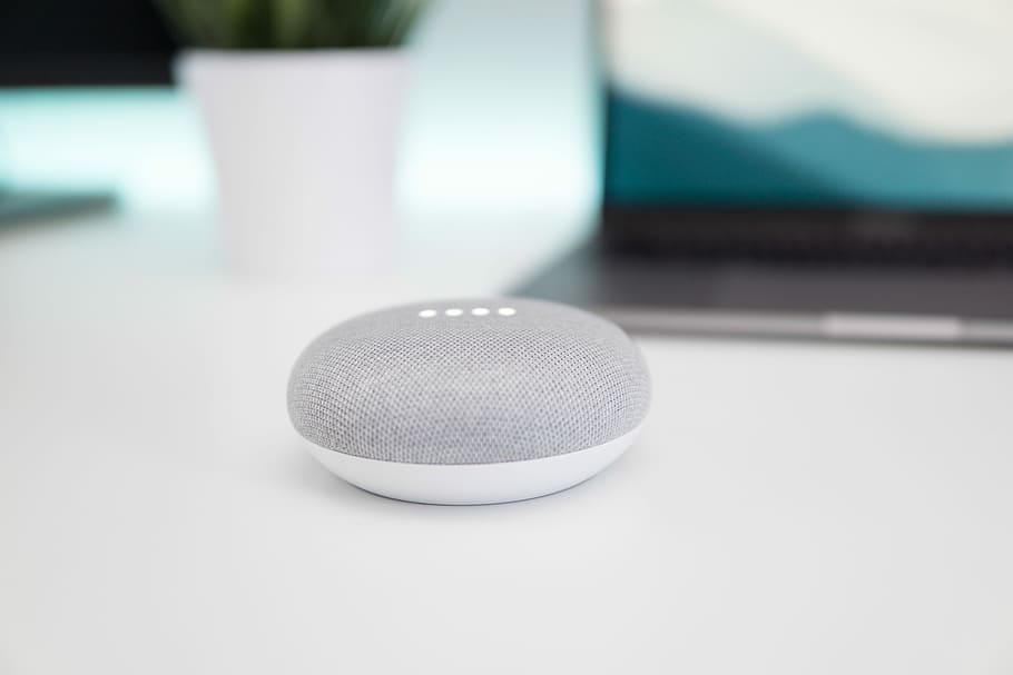 turned on gray and white Google Home Mini speaker on white surface, chalk Google Home Mini