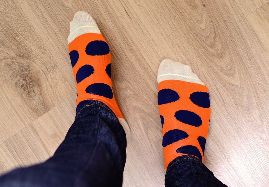 person in orange and blue socks, feet, floor, wood, jeans, legs