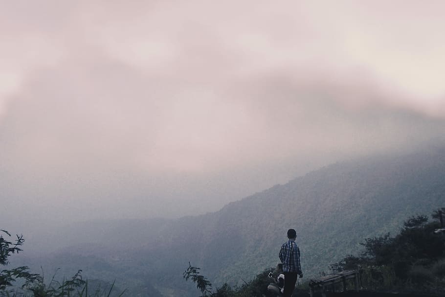 person standing on mountain surrounded by fogs, person standing front of mountain HD wallpaper