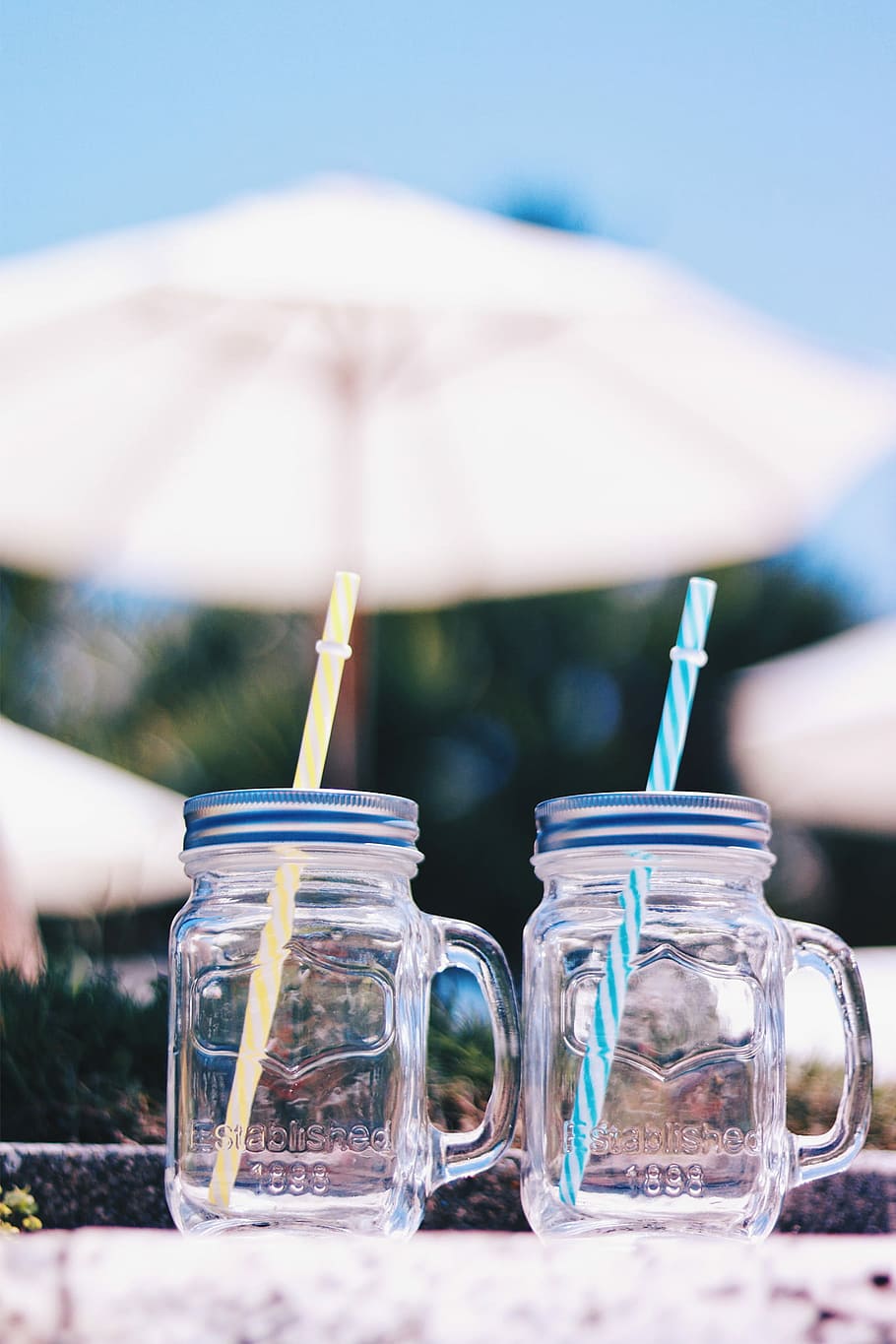 two clear glass mason jar near patio umbrella during daytime
