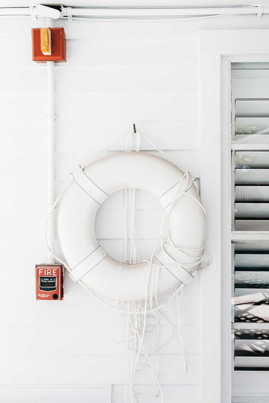 white swim ring beside window, white wall paint room, wood, fire alarm