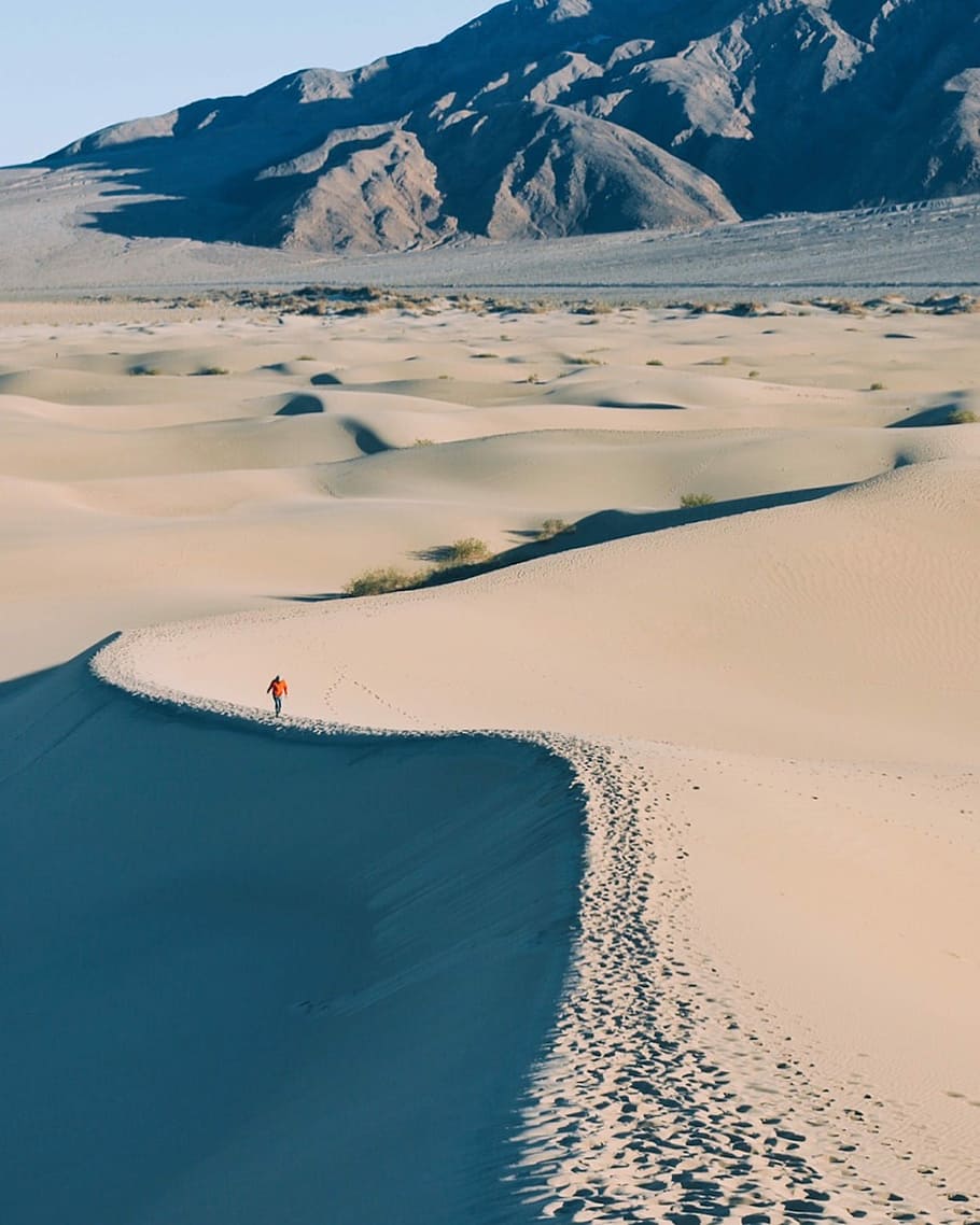 man walking on desert, person walking along the desert near rocky mountains HD wallpaper