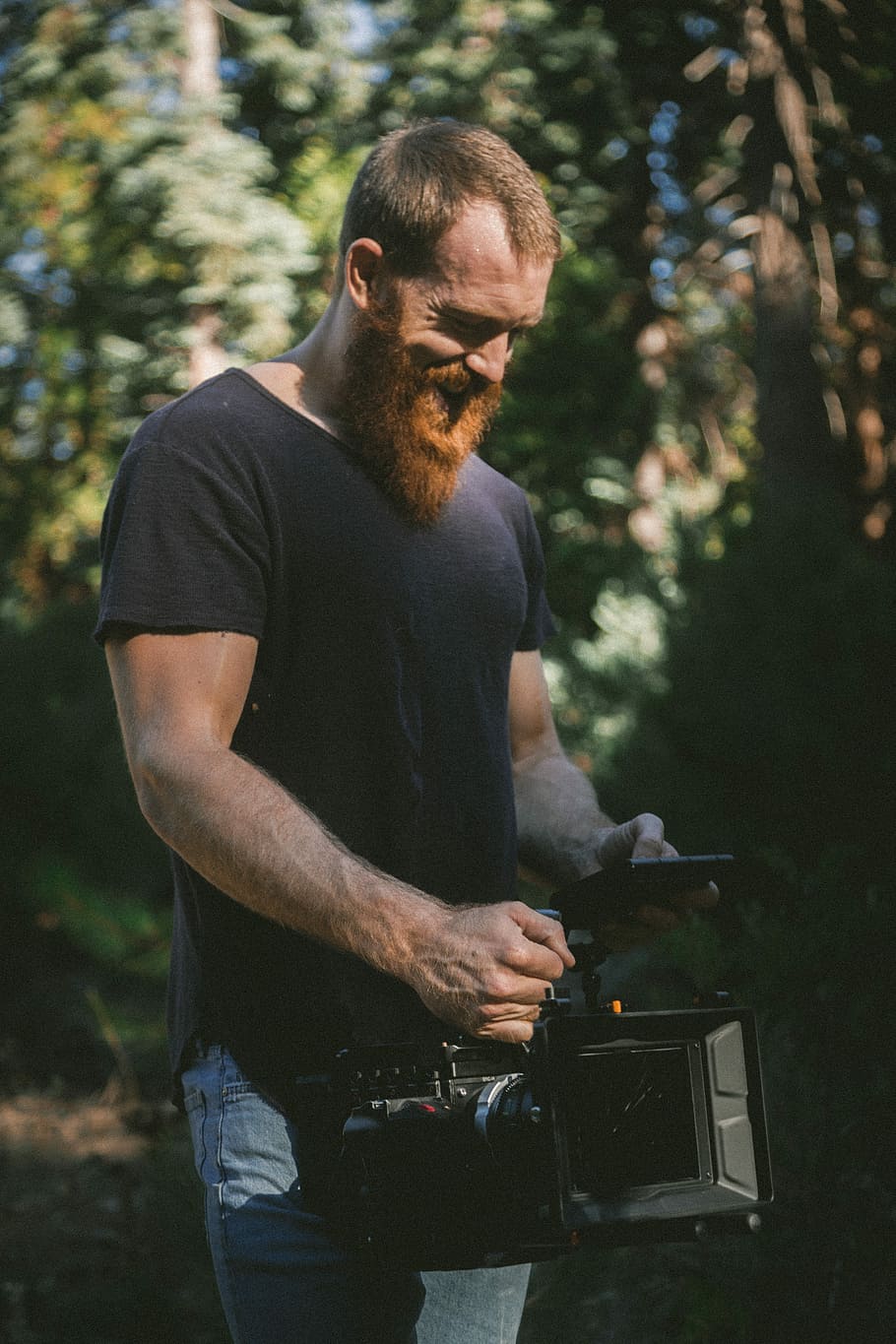 man holding black video recorder in the woods, person wearing black shirt holding professional camera smiling HD wallpaper