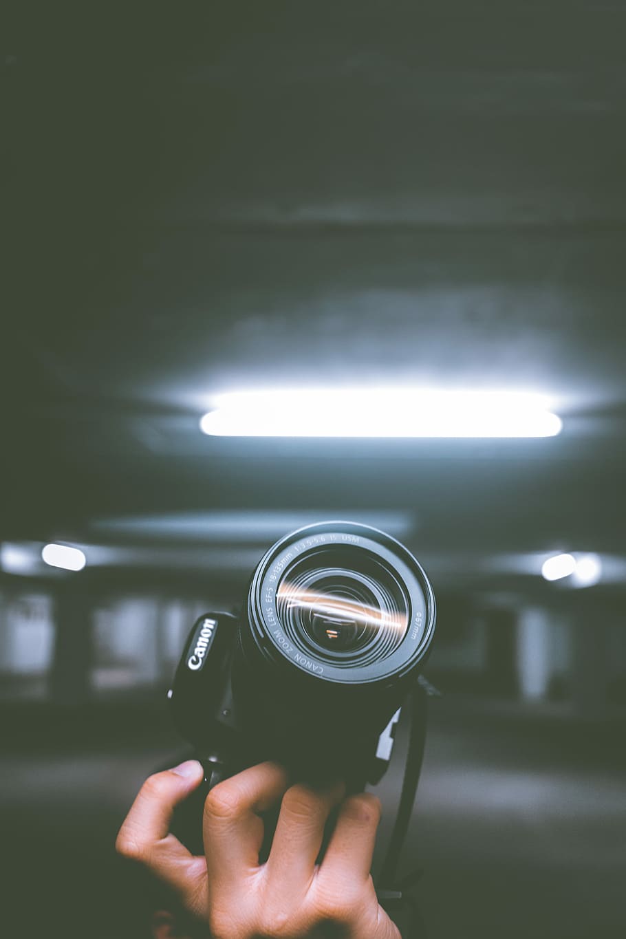 person holding black Canon DSLR camera inside indoor vehicle garage, person holding black Canon DSLR camera HD wallpaper
