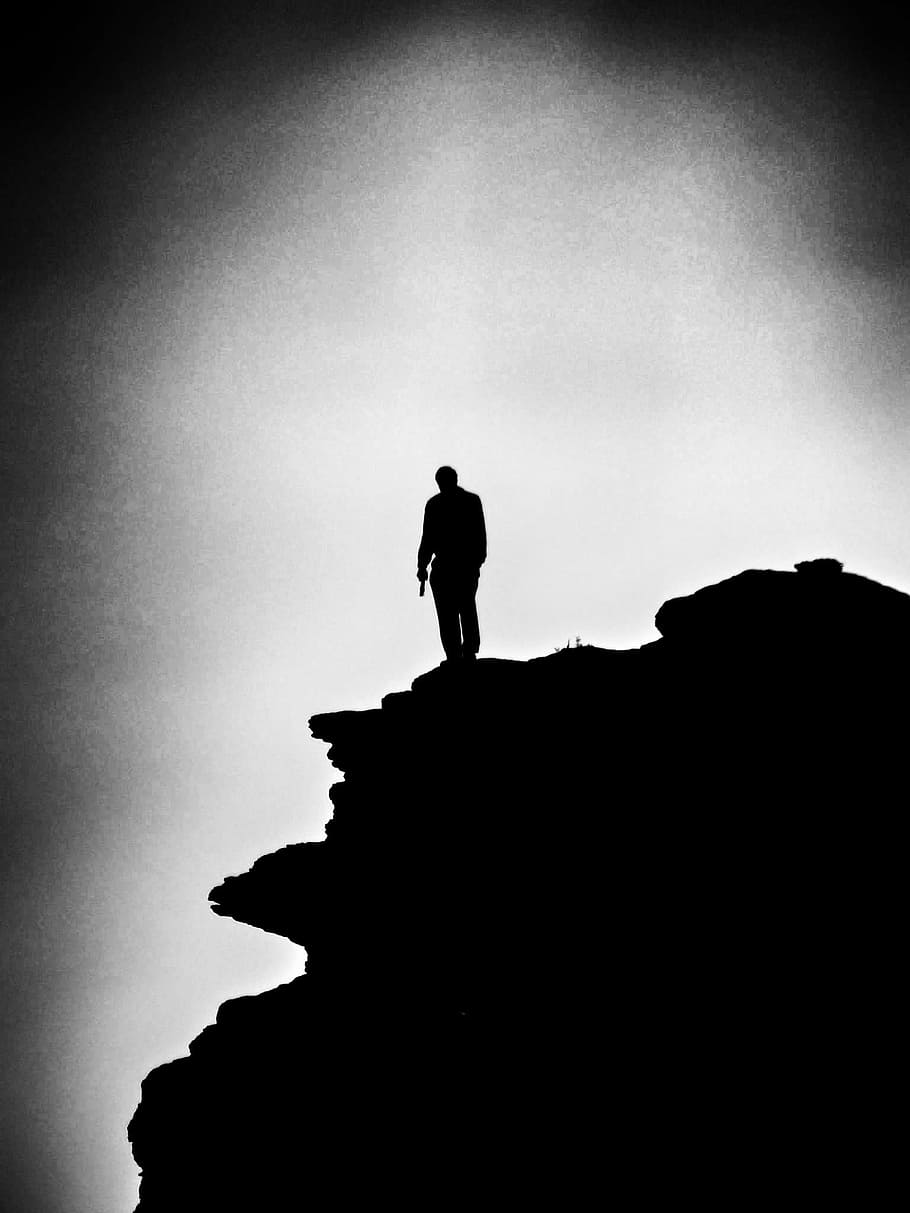 grayscale photo of a man on the top of mountain, loner, alone