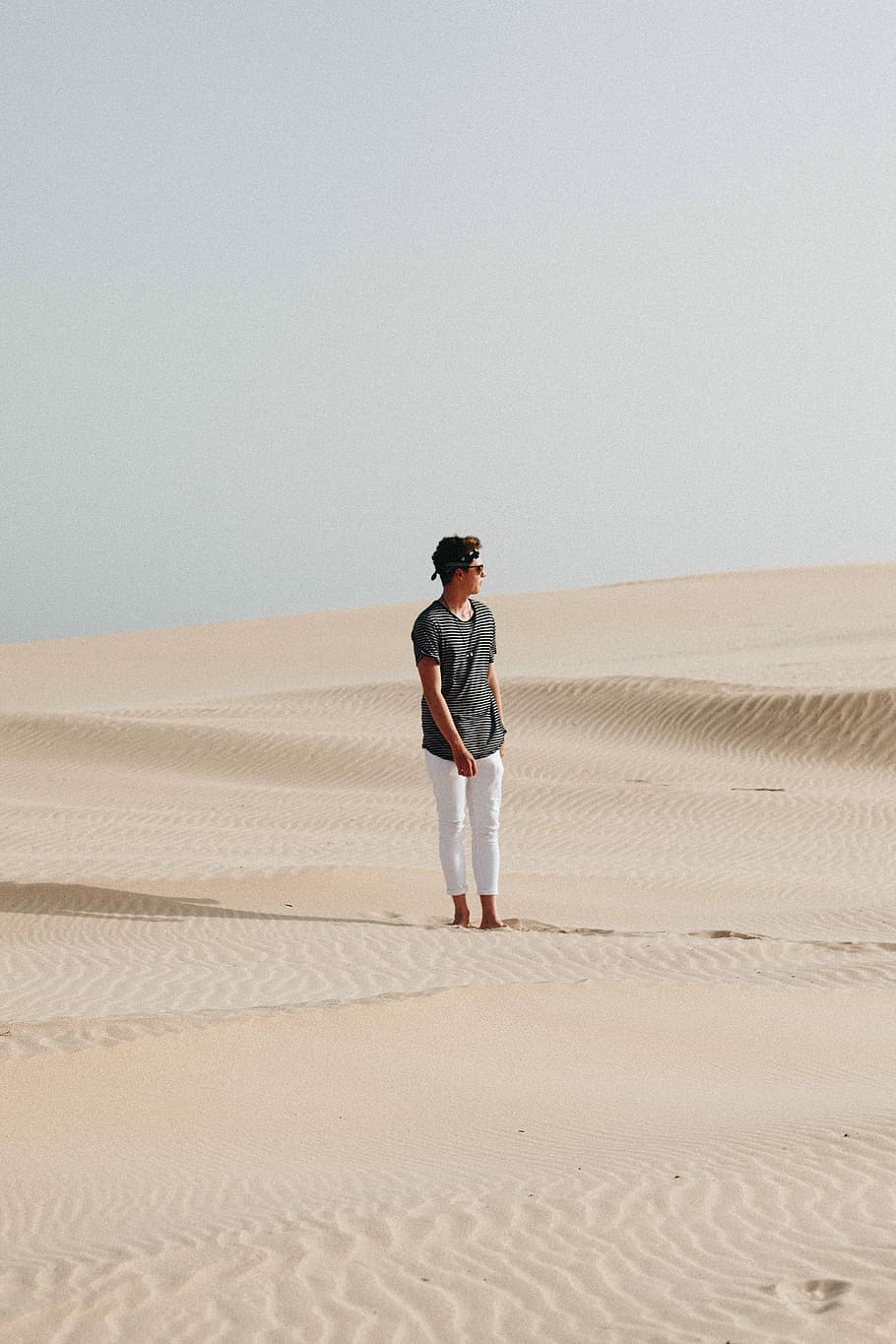 man in the middle of desert, man standing on desert under gray sky HD wallpaper