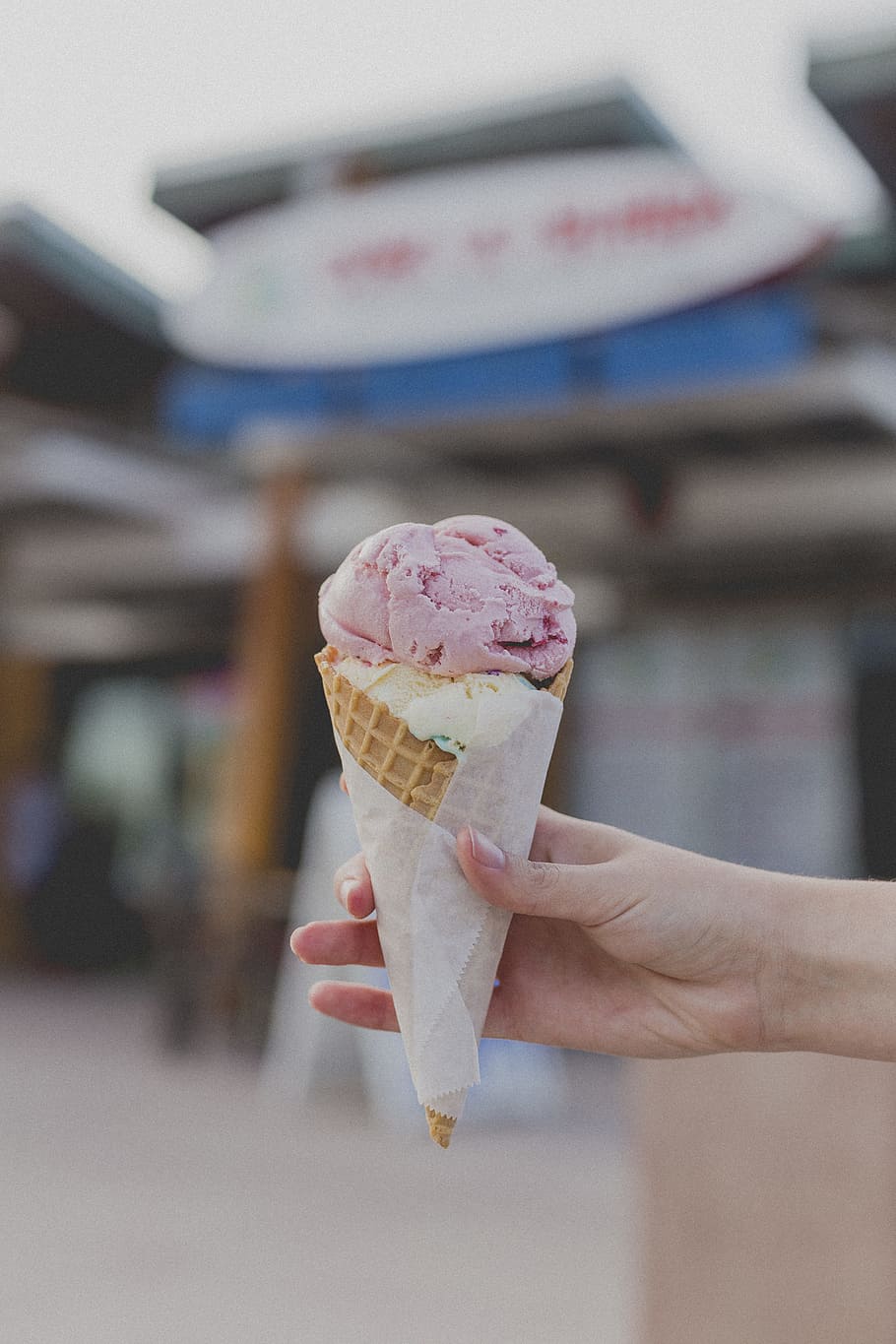 person holding strawberry ice cream, person holding ice cream cone