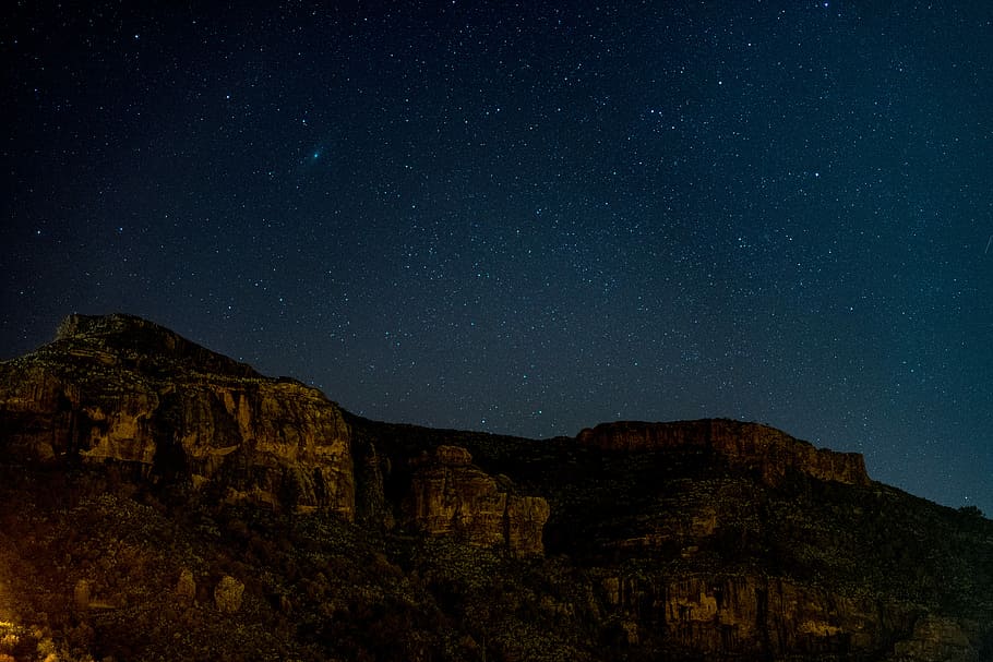 rock mountain under starry night, brown mountain at nighttime HD wallpaper