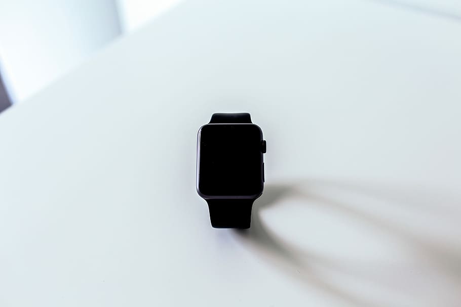 Apple Watch on white surface, black Apple Watch with sport band