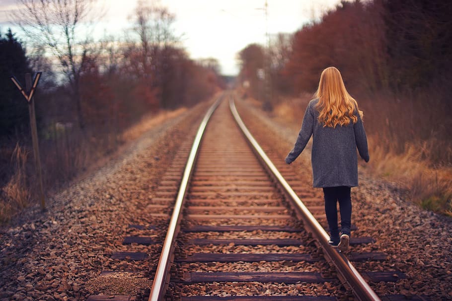 woman walking on rail road, stainless steel train rail, train track