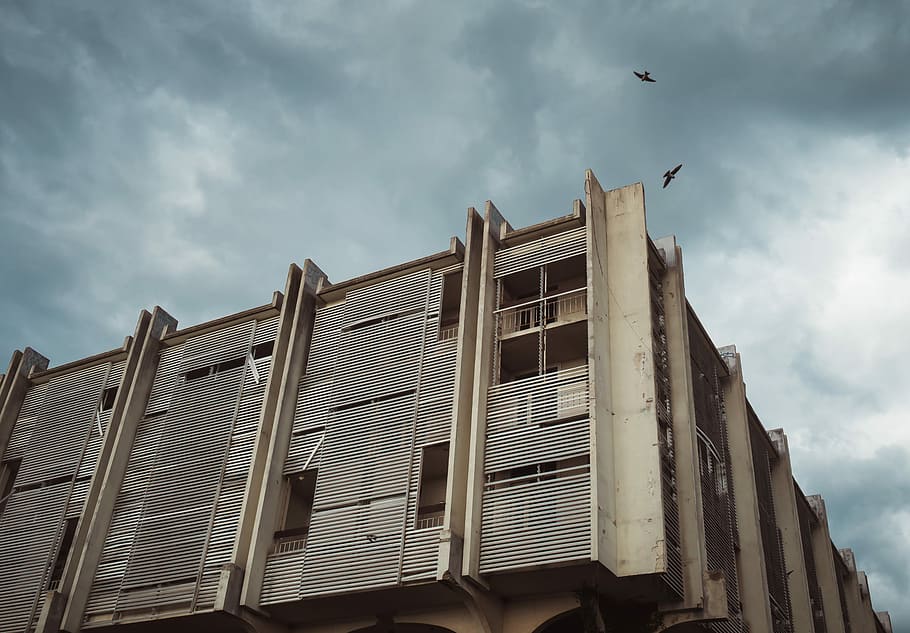 low angle photography of white concrete building, beige concrete building under cloudy sky HD wallpaper