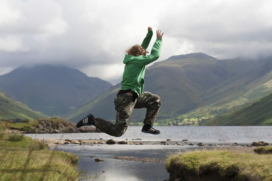 person jumping cliff, man in mid air near body of water, mountain HD wallpaper