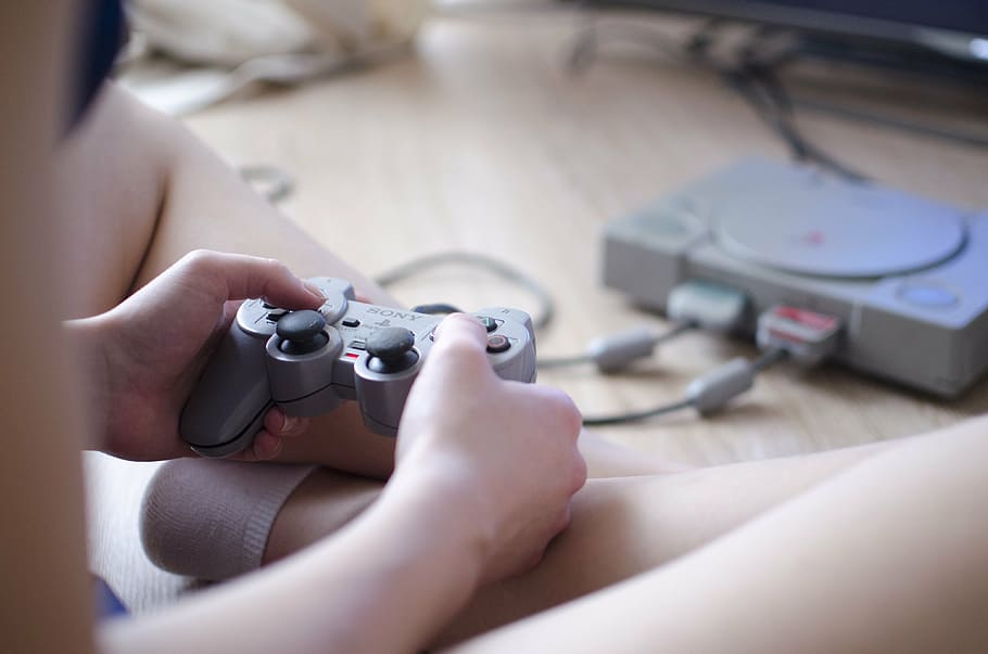 person holding Sony PS1 controller, joystick, video game, girl