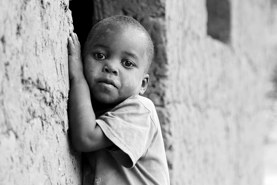 grayscale photo of toddler leaning beside concrete wall, children of uganda