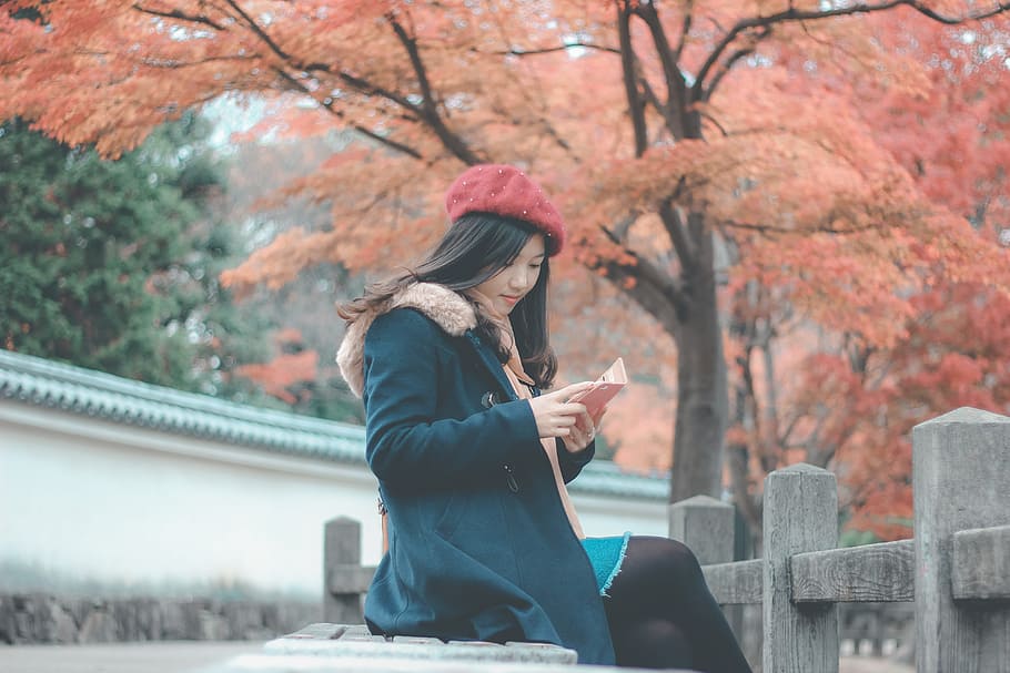 Woman in Blue Parka Jacket Sitting on Grey Concrete Bench Reading Book HD wallpaper