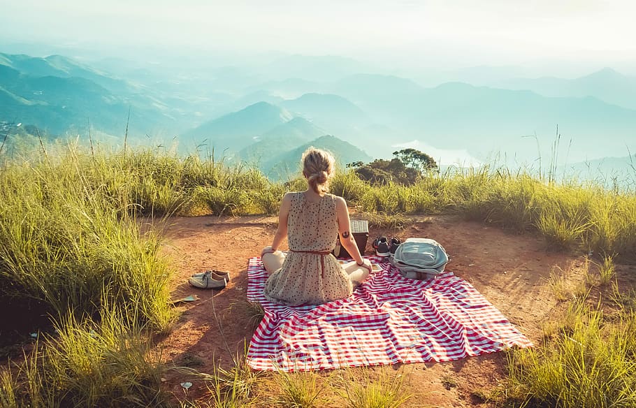 woman wearing gray sleeveless dress sitting on the picnic mat, woman sitting on multicolored textile looking on mountains during daytime HD wallpaper