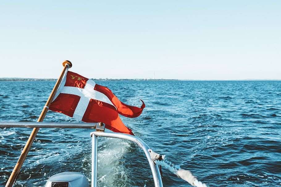 red and white flag, boat with red and white flag with cross under during daytime