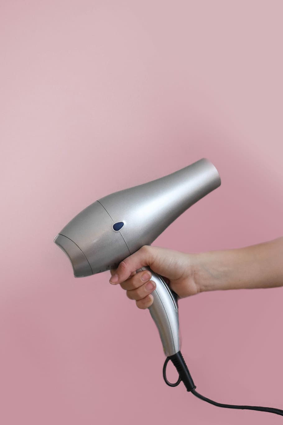 person holding gray corded hair dryer, person holding silver hair dryer