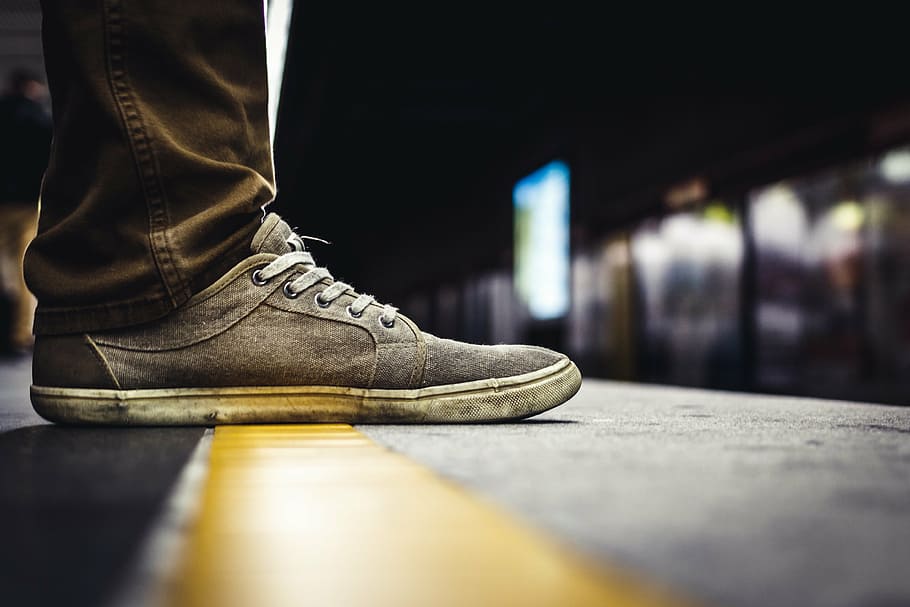 selective focus photo of person wearing gray and white suede low-top shoe and brown jeans over gray and yellow concrete ground, HD wallpaper