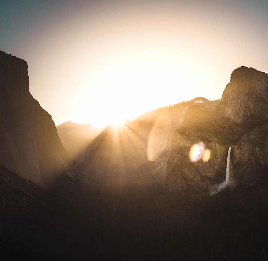 sun shining through mountain ranges, brown mountains against light at sunset HD wallpaper