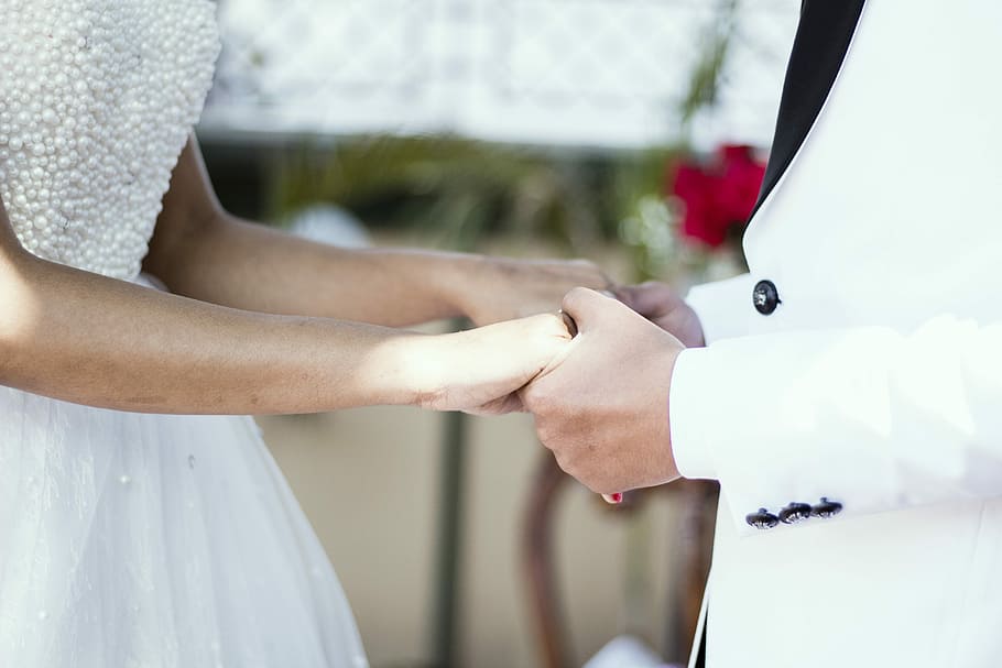 bride and groom holding hands, man holding woman's hand close-up photo