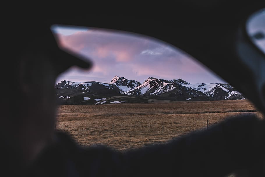 man sitting inside the car looking at snow capped mountain under white cloudy sky, person sitting inside vehicle looking at the mountain HD wallpaper