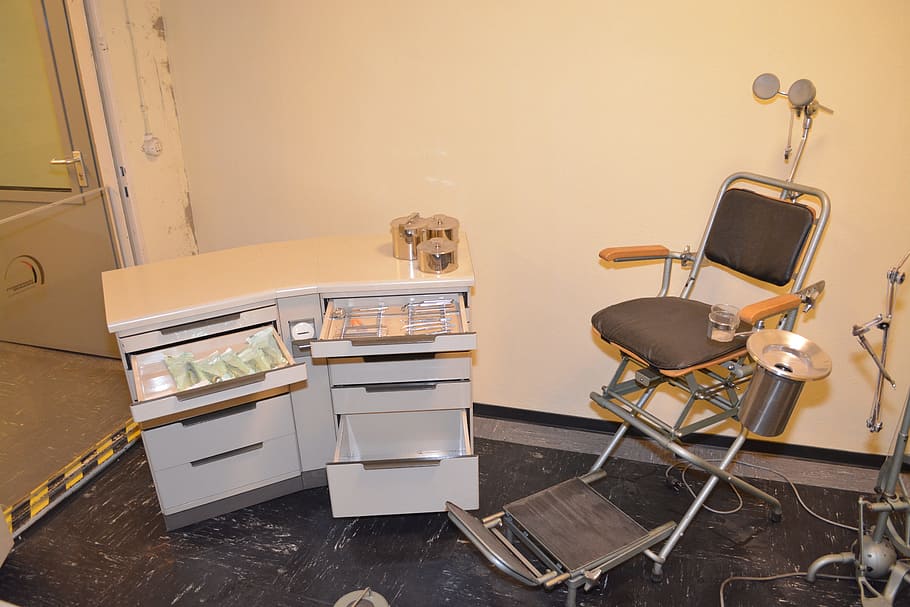 black dentist chair with grey wooden drawer chest, government bunker