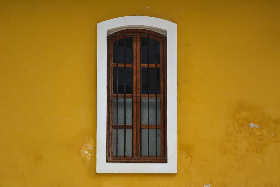closed window on wall, mirror with brown wooden frame install in yellow and white wall