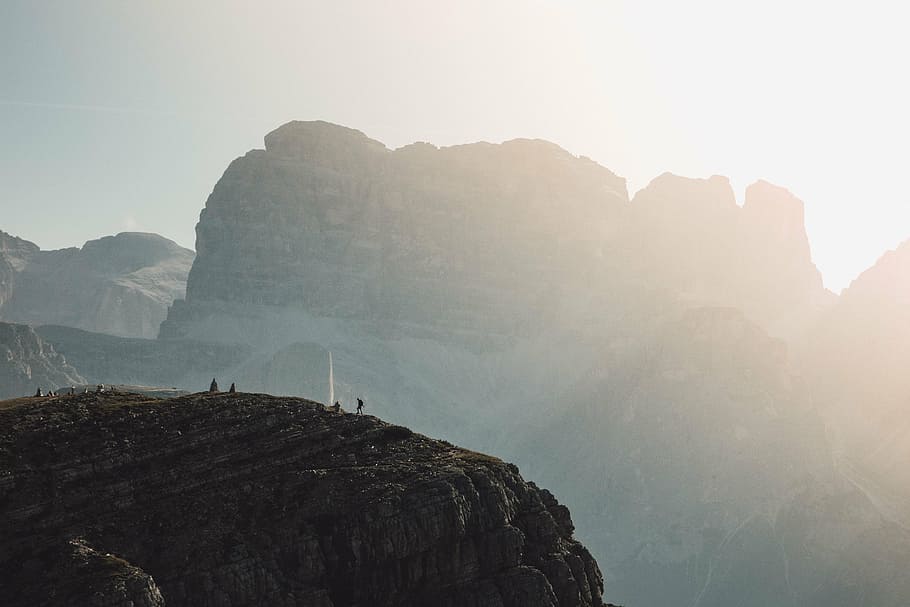 photo of several people on rocky hill during daytime, standing HD wallpaper