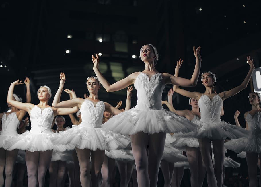 group of ballerinas dancing while raising both hands, ballerinas performing on stage