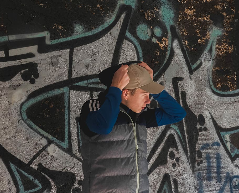 man standing near wall art, man putting hoodie over cap, male HD wallpaper