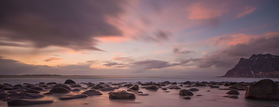 rock formation near shoreline during golden hour, rocks on shore with distance to mountain during sunrise HD wallpaper