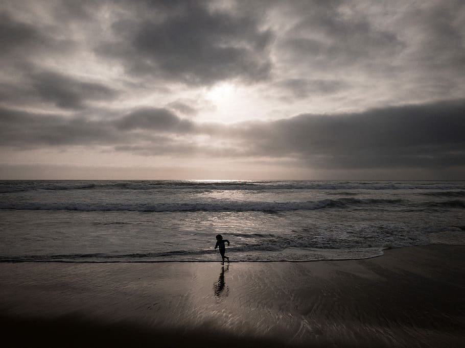 silhouette of person near beach, silhouette of toddler standing beside sea shore during daytime HD wallpaper