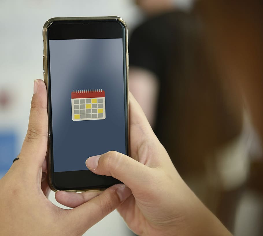 person holding iPhone displaying calendar, telephone, touch HD wallpaper