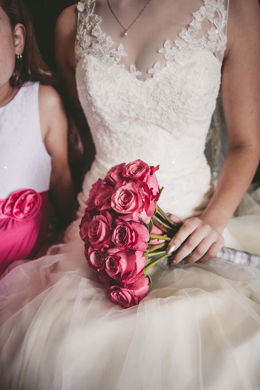 woman wearing white floral wedding dress holding bouquet of rose, woman holding a bouquet of pink roses