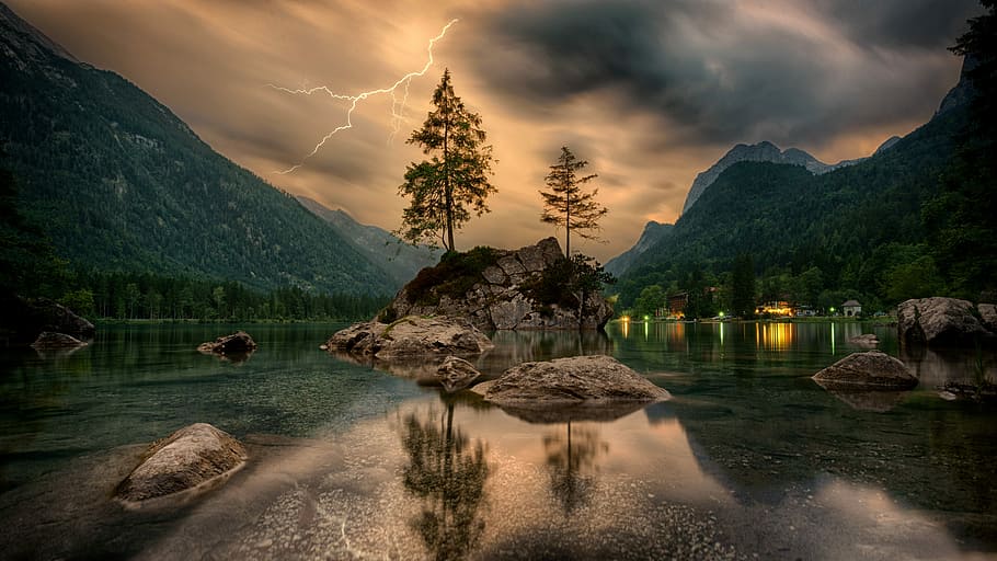 green and brown tree painting, reflective photography of trees, rocks, and mountain with lightning strike in background