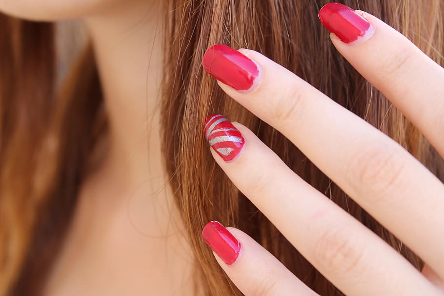 close up view of women's red polished fingernails, nail polish