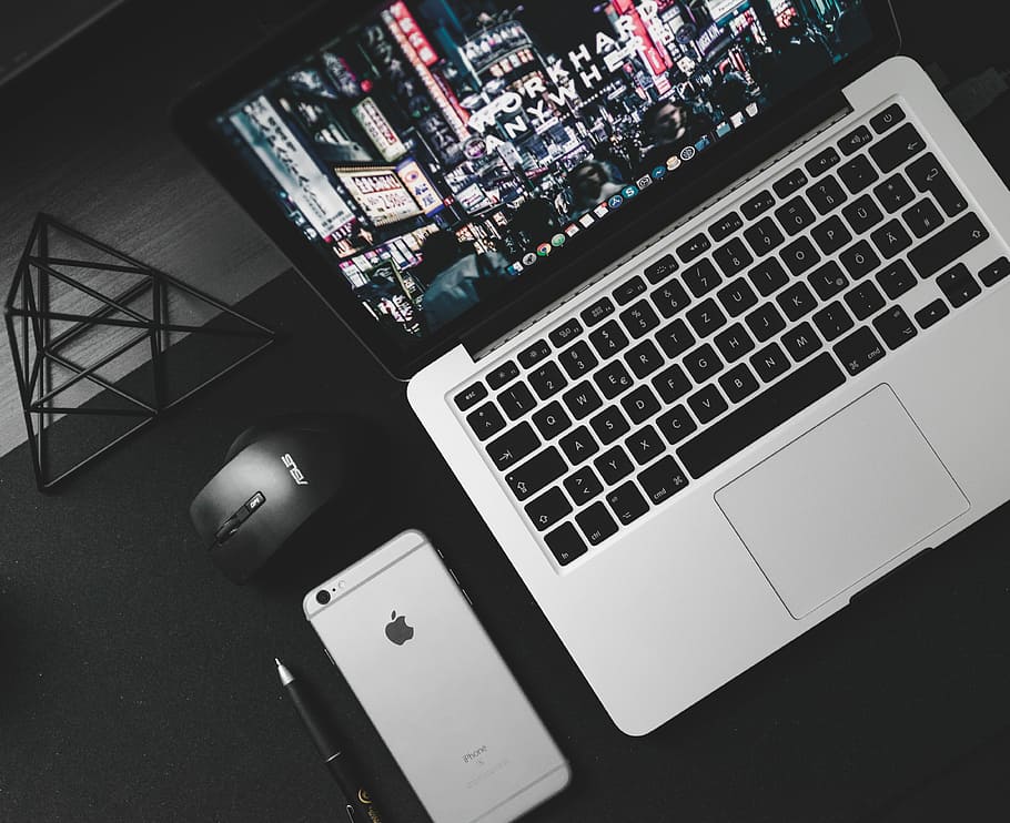 turned on MacBook Pro beside space gray iPhone 6s, black ballpoint pen, and black Asus cordless optical mouse on top of table, MacBook Pro and space gray iPhone 6 HD wallpaper