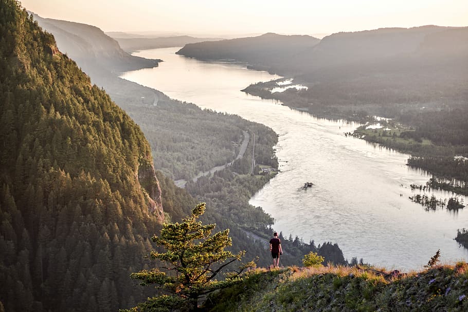 landscape photo of person on top of hill near body of water HD wallpaper